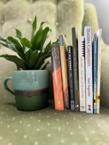 Books along with a plant in a cup kept on a sofa
