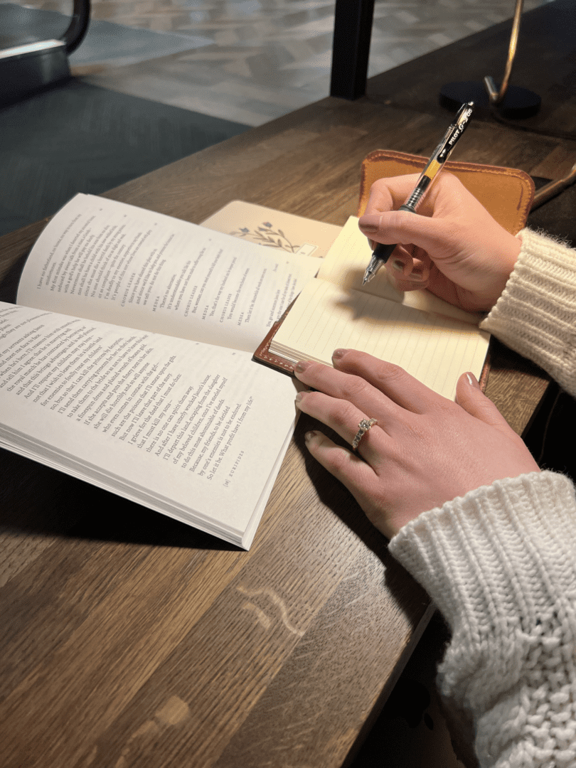 Close-up of hands writing beside open book