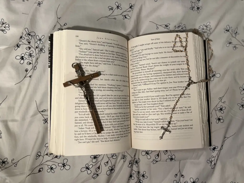 A cross sign on a book lying on a bed