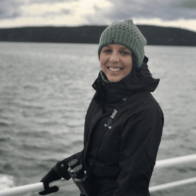 A woman wearing a hat and jacket on a boat.