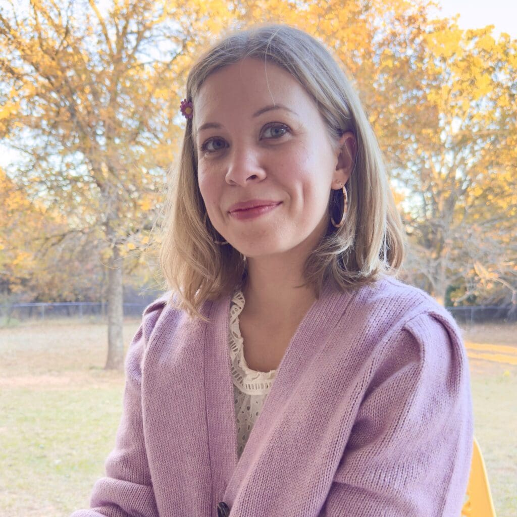 Woman smiling outdoors in autumn scenery.