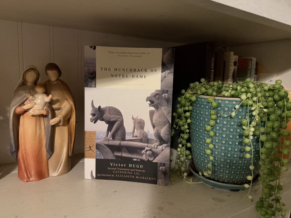 A small nativity scene, a book, and a decorative green vase on a shelf.
